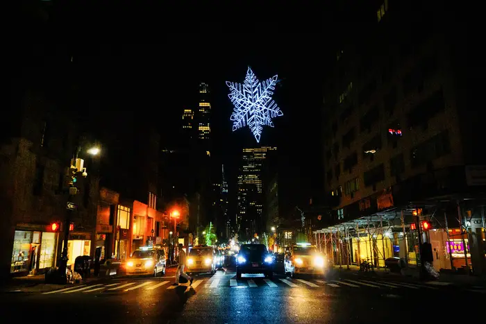 A lit snowflake hangs above a New York City intersection.
